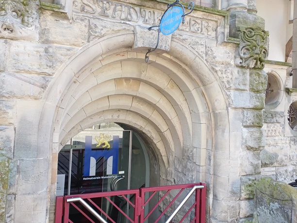 Heimatinfo Wunstorf Ein rotes Tor führt ein paar Treppen nach unten in die Wunstorf-Info.