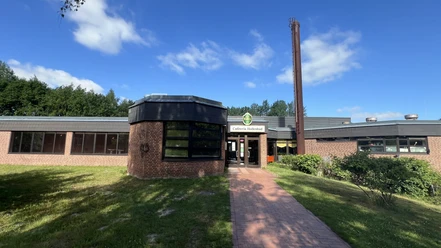 Das rote Backsteingebäude des Hallenbads Worpswede mit dem Eingangsbereich an einem Sonnentag.