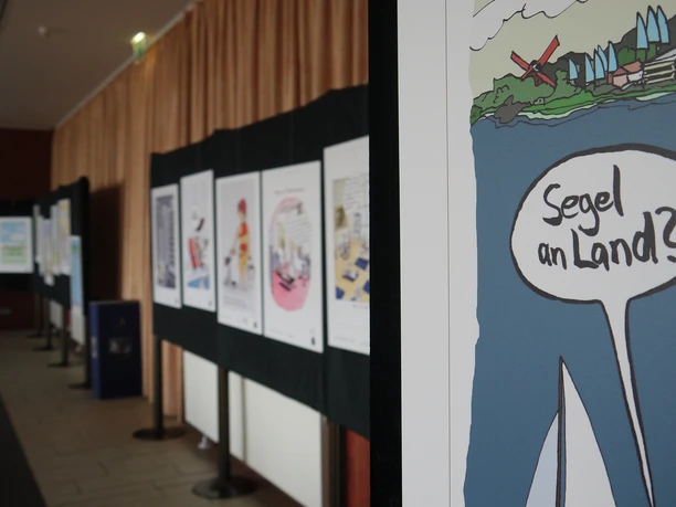 segel an land.JPG Einblick in die Ausstellung "Das Goldene Segel" mit Fokus auf einem Cartoon: "Segel an Land?".