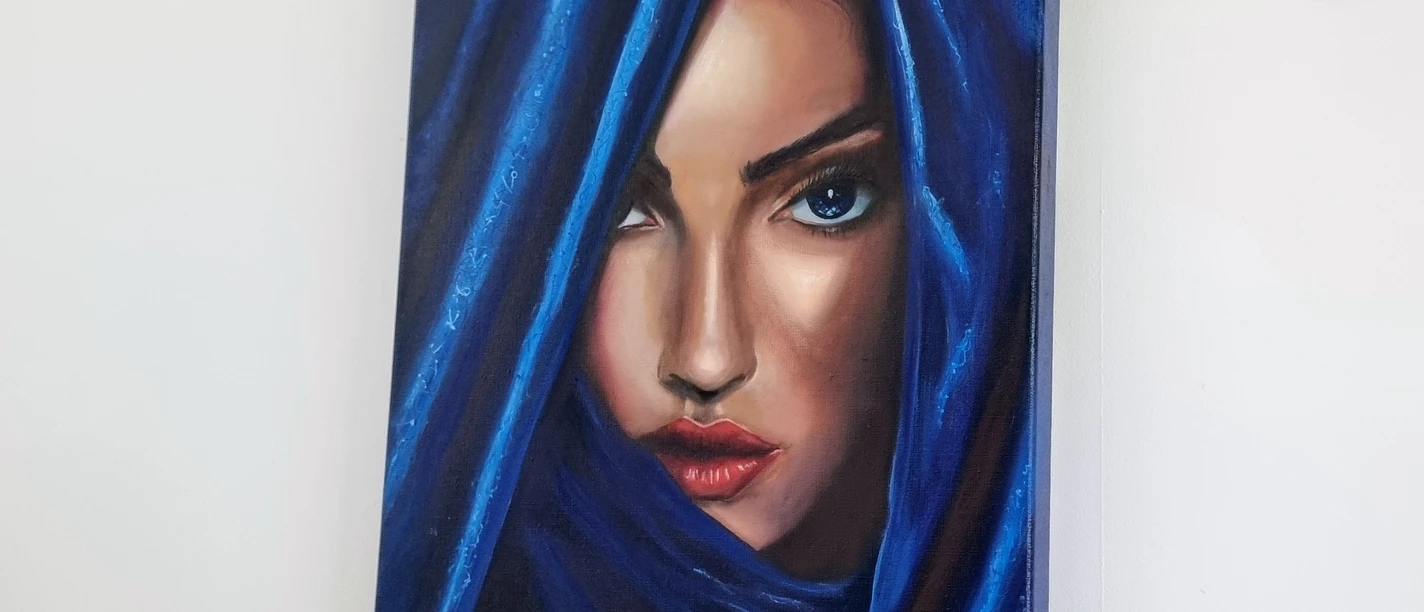 Ausstellung "Trotz.dem" Yvonne Brueckner Porträt einer Frau mit blauen Augen, die durch einem blauen Vorhang schaut, der ihr Gesicht umrahmt.