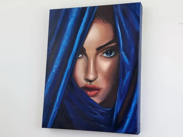 Porträt einer Frau mit blauen Augen, die durch einem blauen Vorhang schaut, der ihr Gesicht umrahmt.