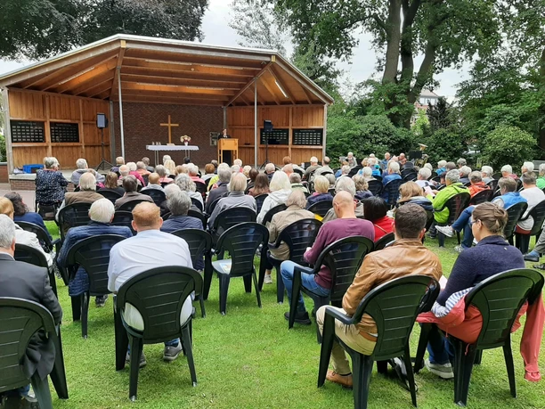 Gottesdienst beim "Fest der 1000 Laternen".jpg Gottesdienst im Freien: Viele Menschen sitzen auf Stühlen vor einer Bühne mit Altar und Kreuz.