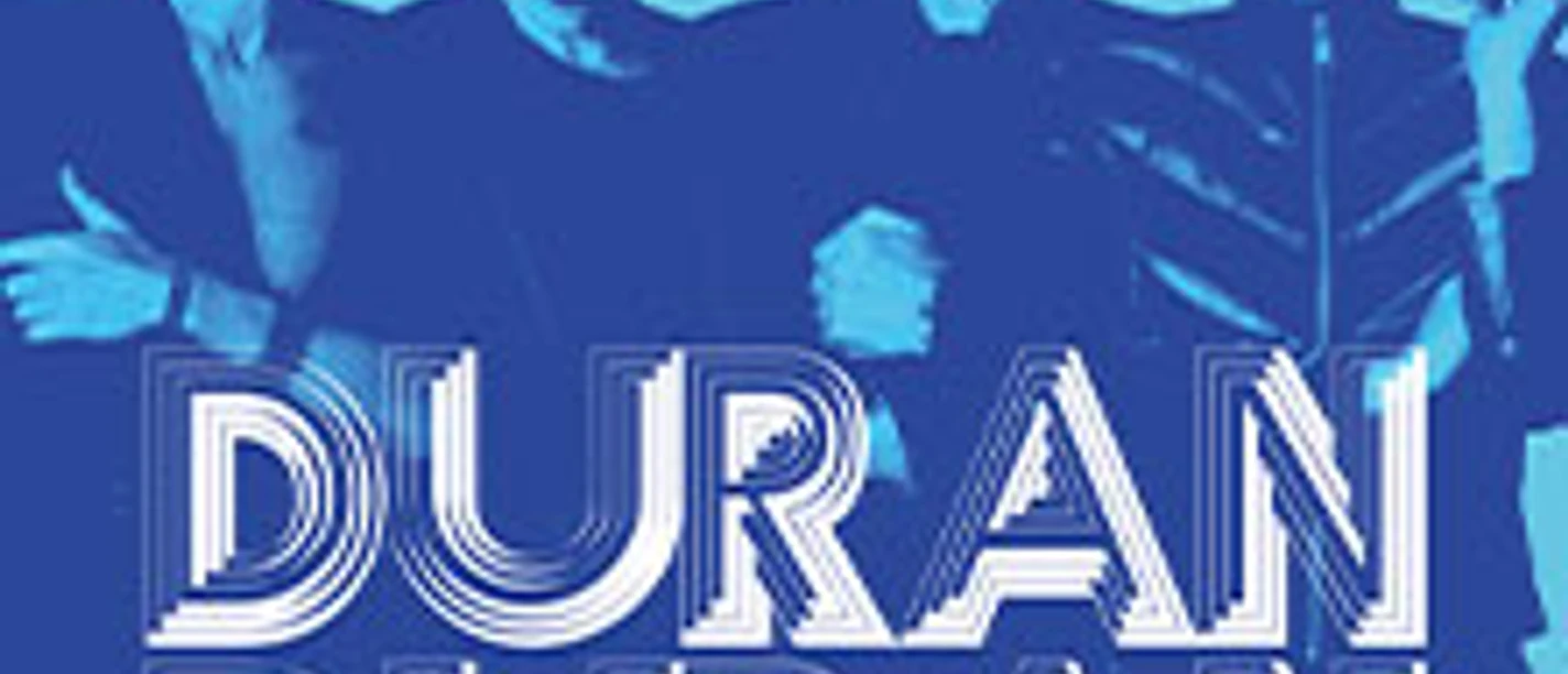 Vier Personen posieren vor blauem Hintergrund mit großem Schriftzug DURAN DURAN.