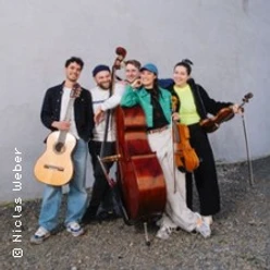 Fünf junge Musiker stehen eng beisammen und halten Gitarre, Kontrabass, Geige und weitere Instrumente.