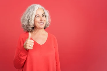 Woman winking as she gives a thumbs up in approval Woman winking as she gives a thumbs up in approval