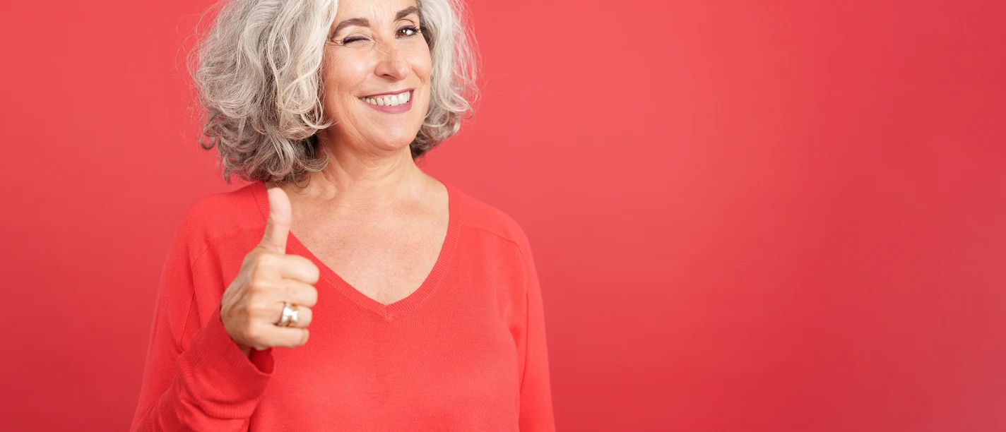 Woman winking as she gives a thumbs up in approval Woman winking as she gives a thumbs up in approval