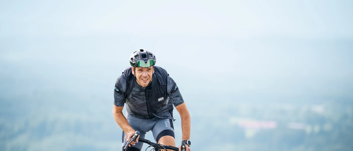 2-Seen-Tour Radfahrer auf Asphalt vor hellen Bergen und weiter Sicht, Bewegung und Naturgefühl.