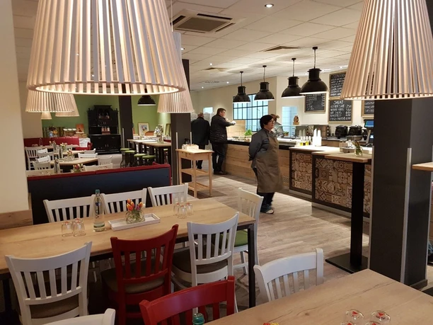 schmeckwerk-gastraum Gastraum mit Holztischen, roten und weißen Stühlen