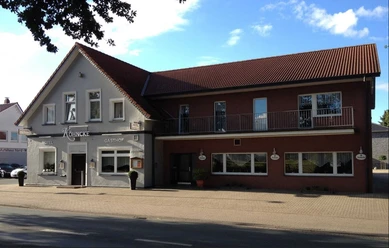 Köhncke's Hotel Das Foto zeigt Köhncke's Hotel, ein zweistöckiges Gebäude mit grauer und roter Fassade sowie einem Satteldach.