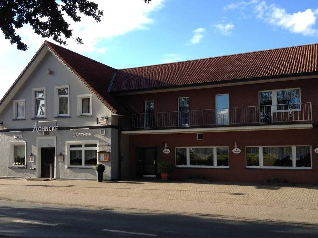 Köhncke's Hotel Das Foto zeigt Köhncke's Hotel, ein zweistöckiges Gebäude mit grauer und roter Fassade sowie einem Satteldach.
