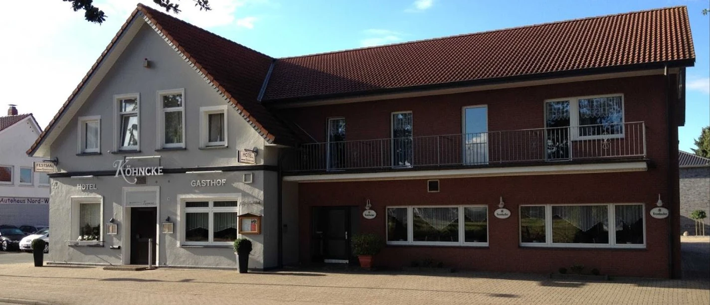 Köhncke's Hotel Das Foto zeigt Köhncke's Hotel, ein zweistöckiges Gebäude mit grauer und roter Fassade sowie einem Satteldach.