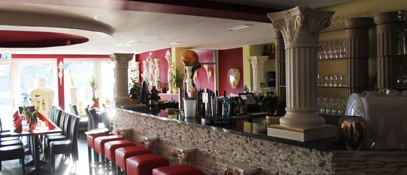 Sparta Innenansicht eines Restaurants mit antiken griechischen Dekorationen, roten Sitzpolstern und Bartheke.