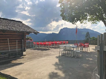 Terrace Gasthaus Gsässweid Betonierte Terrasse mit roten Tischen und Gartenstühlen Concreted terrace with red tables and garden chairsTerrasse bétonnée avec tables et chaises de jardin rouges