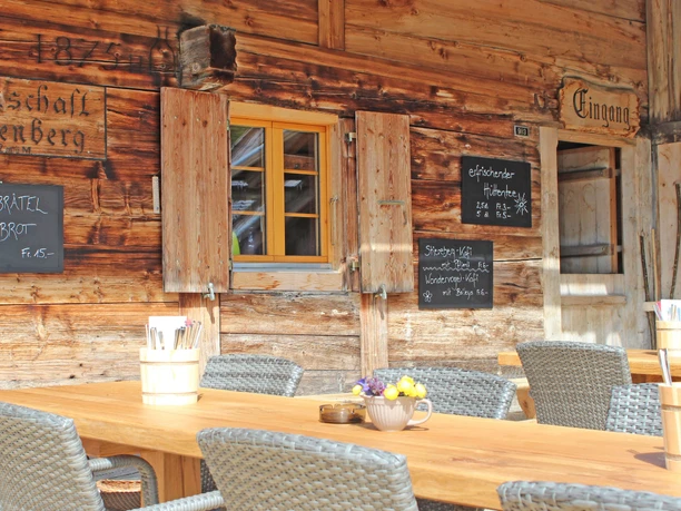 Stierenberg mountain restaurant terrace with summer sun Wooden table with gray chairs in front of the house wall of the inn