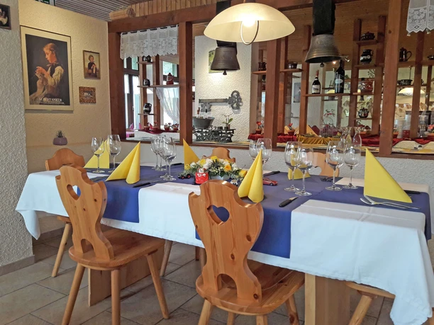 Restaurant Wirieblick Ankerstübli Festlich gedeckter Tisch mit gelben Servietten, blauem Tischtuch und Blumendeko
