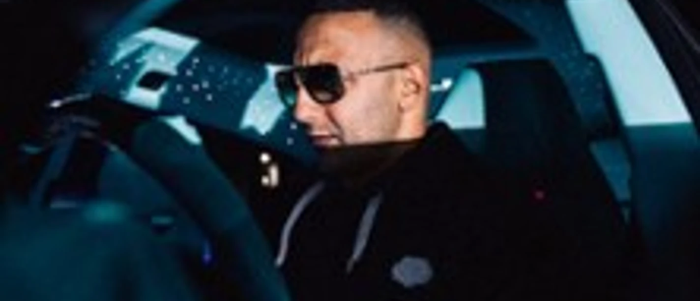 Person mit Sonnenbrille sitzt im dunklen Fahrzeuginterieur bei gedämpftem Licht