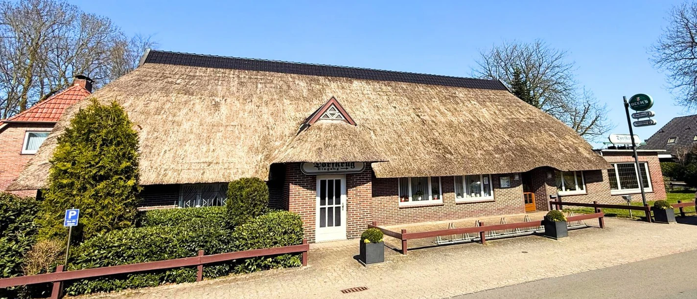 Eingang zum Dorfkrug Hankhausen Frontansicht des Dorfkrugs Hankhausen, ein Backsteingebäude mit traditionellem Reetdach.