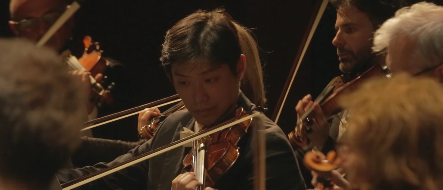 VA für Stadjubiläum.jpg Nahaufnahme eines Geigers, der mit seinem Orchester bei einer Jubiläumsveranstaltung spielt.