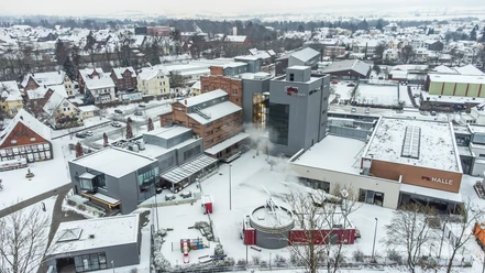 Winterliche Luftaufnahme des PS.SPEICHER Areals in Einbeck mit schneebedeckten Dächern.