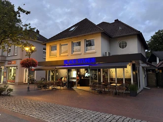 Blaue-Stunde-Bad-Zwischenahn-Aussenansicht.jpg Außenansicht der Bar Blaue Stunde in Bad Zwischenahn in der Abenddämmerung mit Außengastronomie.