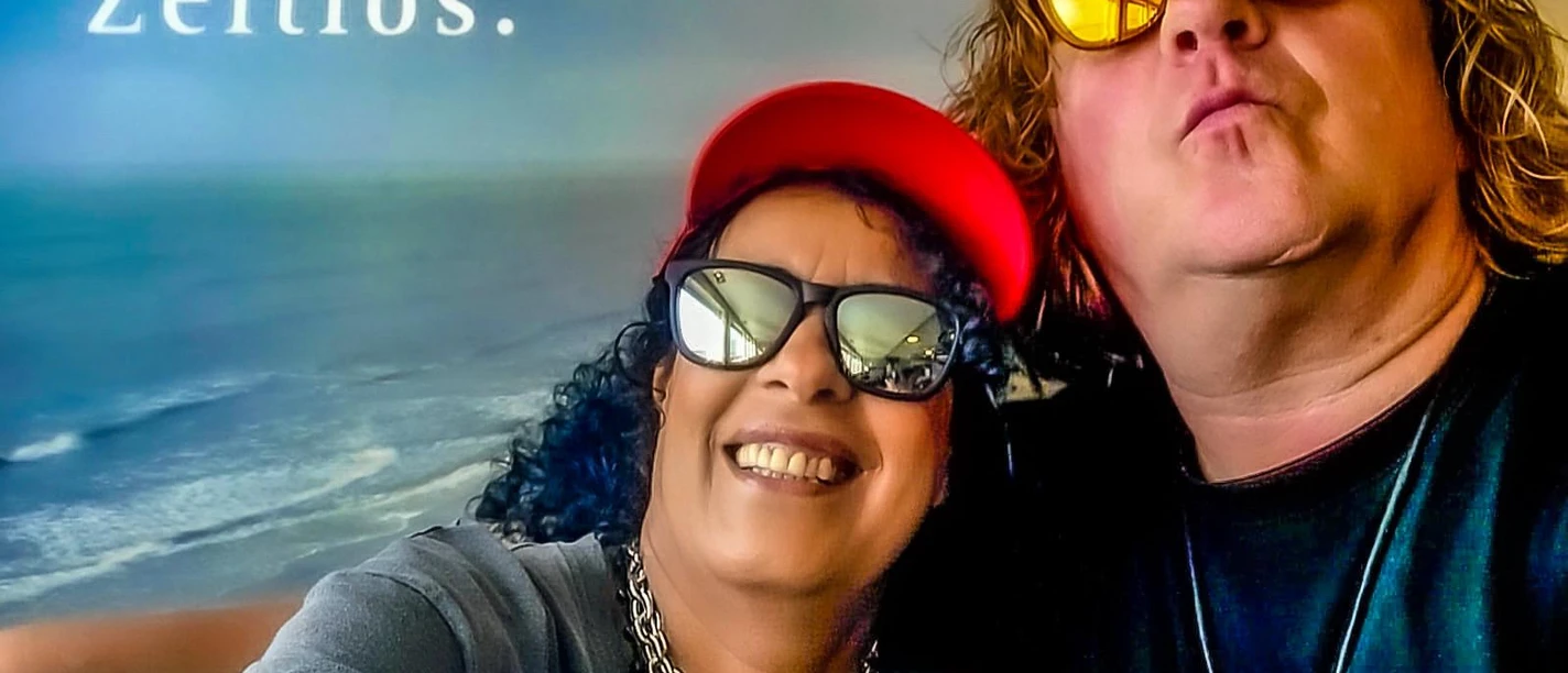 Gerrit Akkermann und Amina Die Musiker Gerrit und Amina als Selfie-Porträt vor einer Meereskulisse mit Schriftzug 'Zeitlos.'.