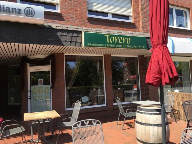 torero Restaurant Torero von außen, Gartentische und Stühle, Sonnenschirm und ein Fass