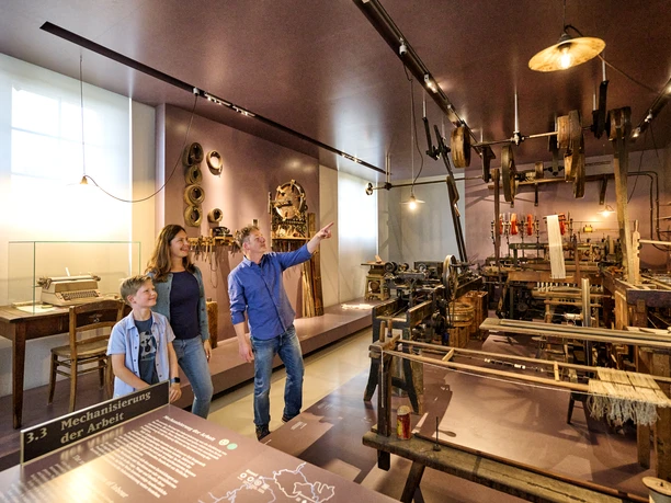 Hessisches Landesmuseum Im Hessischen Landesmuseum stehen drei Personen im Ausstellungsraum. Eine Person zeigt auf ein Exponat.