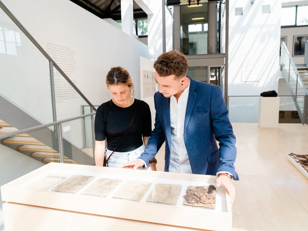 Museum für Sepulkralkultur Zwei Personen schauen sich im Museum Sepulkralkultur ein Exponat an.