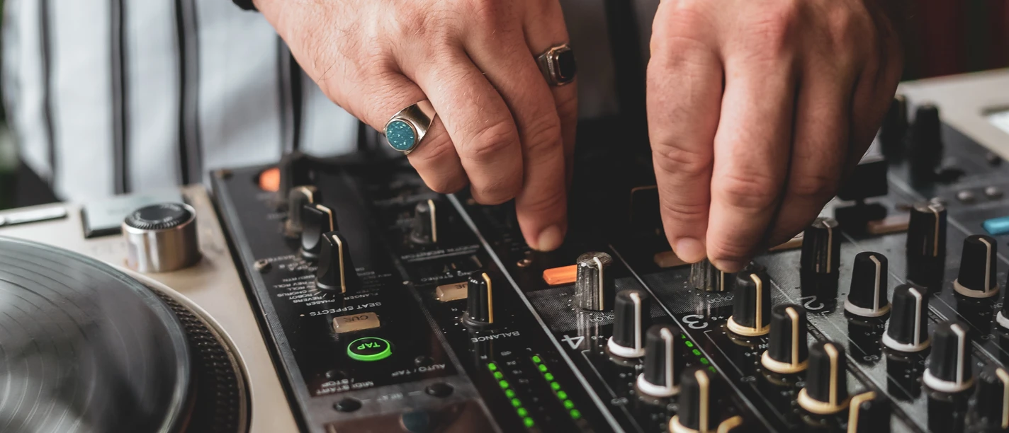 DJ.jpg Nahaufnahme vom DJ Mischboard. Zwei Hände drehen an den Knöpfen.