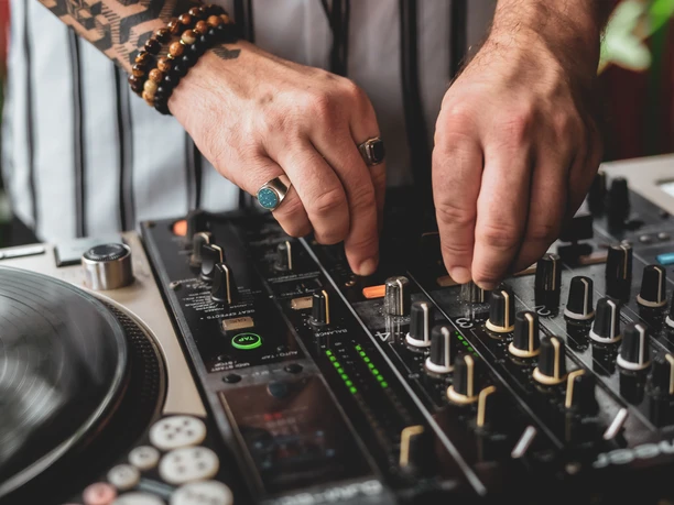 DJ.jpg Nahaufnahme vom DJ Mischboard. Zwei Hände drehen an den Knöpfen.
