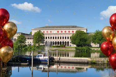 Jubiläum_100 Jahre Stadthalle Mülheim.jpg Stadthalle Mülheim an der Ruhr mit Schriftzug „100 Jahre” und umgeben von roten und goldenen Ballons