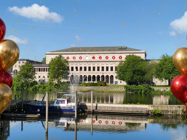 Jubiläum_100 Jahre Stadthalle Mülheim.jpg Stadthalle Mülheim an der Ruhr mit Schriftzug „100 Jahre” und umgeben von roten und goldenen Ballons