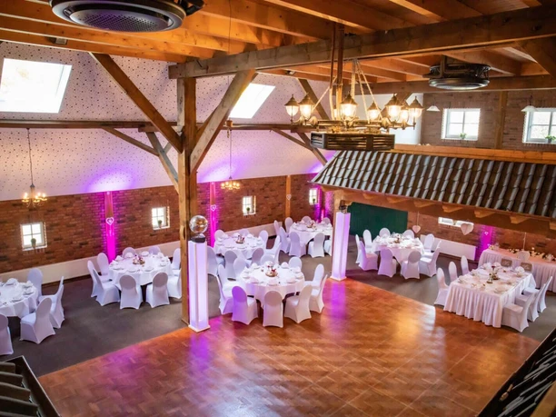Meta-Goldener-Adler-Bad-Zwischenahn-Hochzeit1.jpg Großer Festsaal mit Holzbalken, festlich für eine Hochzeit gedeckten Tischen und Tanzfläche.
