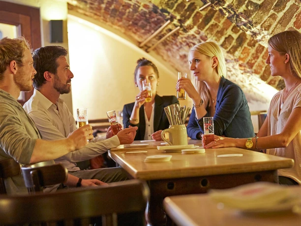 Früh am Dom A group of people are sitting in the vaulted cellar of the brewery.