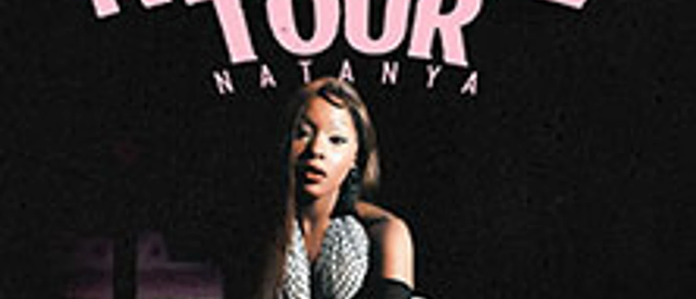 Frau posiert vor dunklem Hintergrund unter dem Schriftzug The Attitude Tour Natanya