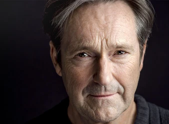 Nahaufnahme des Schauspielers Helmut Zierl, der freundlich in die Kamera blickt.