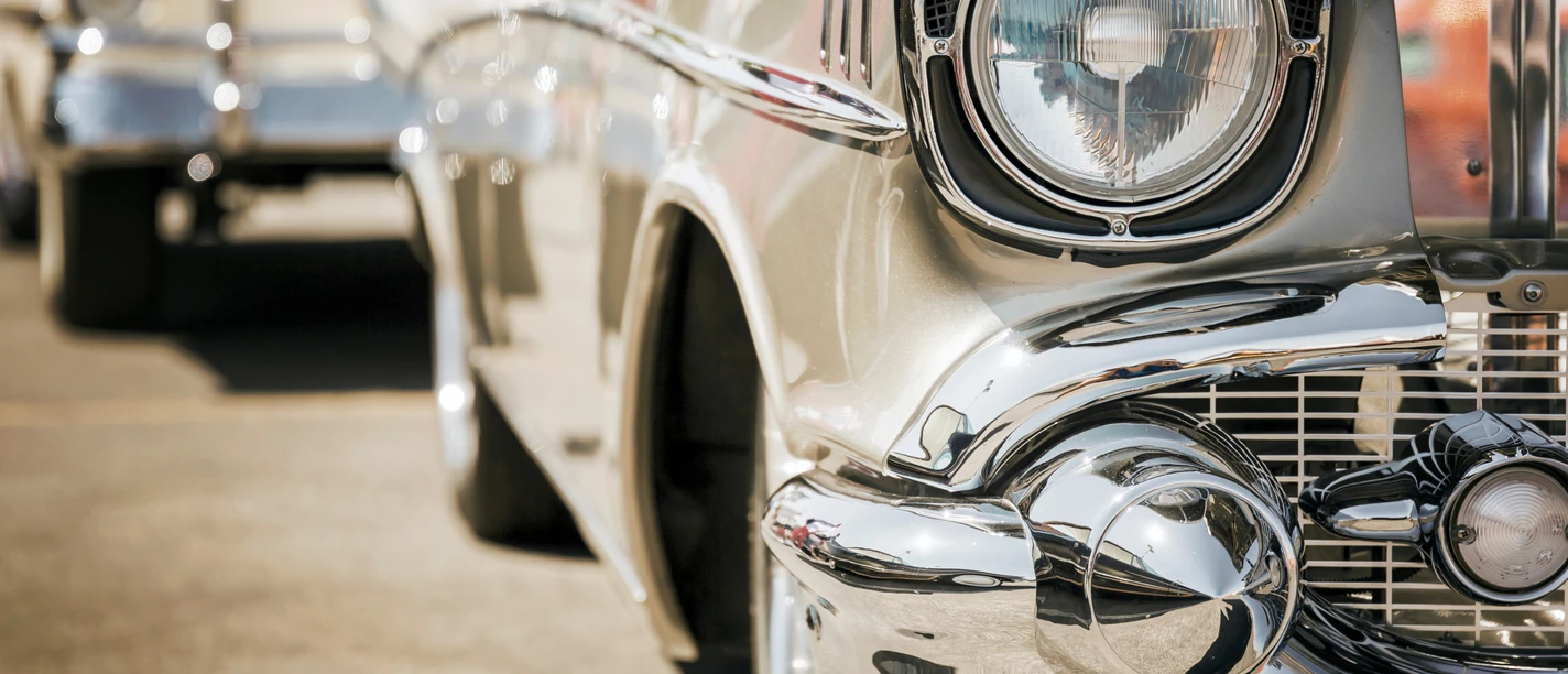 Musterbild Canva.png Nahaufnahme des Scheinwerfers und Chroms eines Oldtimers bei einem Oldtimertrefen.