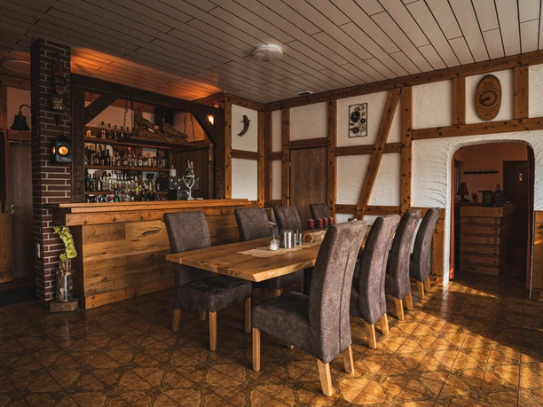 Gastraum des Hotels Resi Gastraum mit Holztischen, gepolsterten Stühlen und Theke im Fachwerkstil.