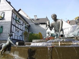 Koboldbrunnen in Morsbach Bronzefiguren am Koboldbrunnen mit Wasserspiel vor Fachwerkhäusern im historischen Zentrum