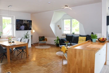 Ferienwohnung-Familie-Baasch-Gesamtansicht 1.JPG Heller, offener Wohn- und Essbereich mit Parkett, Sofa, Esstisch und moderner Küchenzeile.