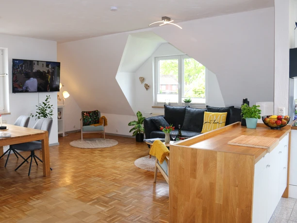 Ferienwohnung-Familie-Baasch-Gesamtansicht 1.JPG Heller, offener Wohn- und Essbereich mit Parkett, Sofa, Esstisch und moderner Küchenzeile.