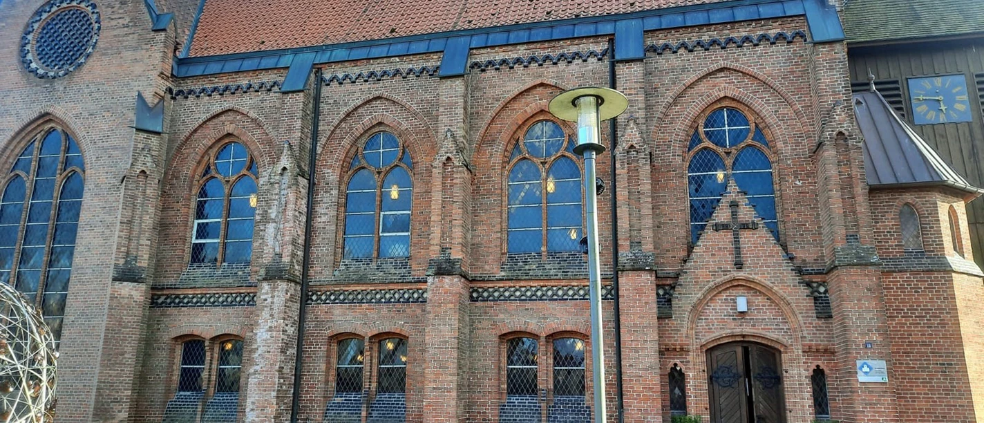 Die Backsteinkirche St. Jakobi in Wietzendorf mit ihren gotischen Fenstern unter blauem Himmel.