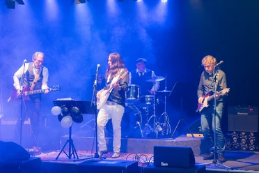 Stickers Gatt Eine vierköpfige Band spielt mit Gitarren und Schlagzeug live auf einer blau beleuchteten Bühne.