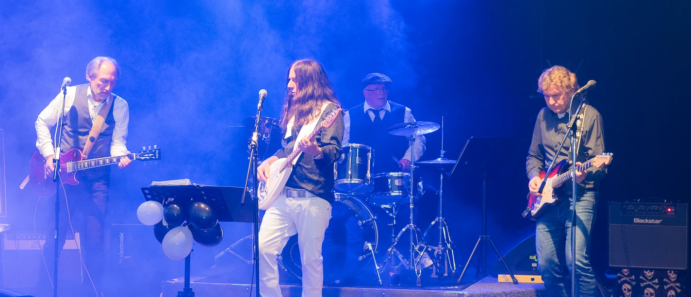 Stickers Gatt Eine vierköpfige Band spielt mit Gitarren und Schlagzeug live auf einer blau beleuchteten Bühne.