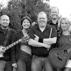 Schuppen 1.7 Fünf gut gelaunte Musiker mit Gitarren und Drumsticks freuen sich auf ihr Open-Air-Konzert.