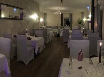 Restaurant & Café Am Steinbruch in Hilter Ein einladendes Restaurant mit elegant gedeckten Tischen, Kerzenlicht und stimmungsvoller Beleuchtung.