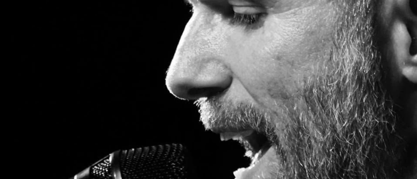 Du, Herr Lampio Ein Musiker singt voller Leidenschaft in ein Mikrofon. Nahaufnahme in Schwarz-Weiß.