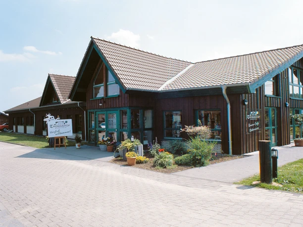 Außenansicht Großes, modernes Holzgebäude mit Satteldach, umgeben von Pflanzen und einem gepflasterten Weg.