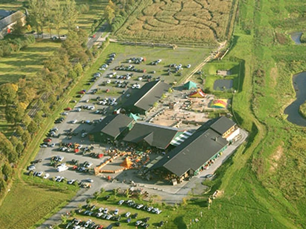 Luftaufnahme Luftaufnahme eines ländlichen Hofes mit Gebäuden, Parkplatz, Maisfeldlabyrinth und grüner Umgebung.