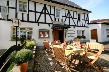 Lindenstübchen Ein traditionelles Fachwerkhaus mit Restaurantterrasse und gedeckten Holztischen im Freien.